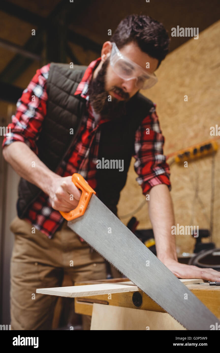 Carpenter sawing a plank of wood Stock Photo
