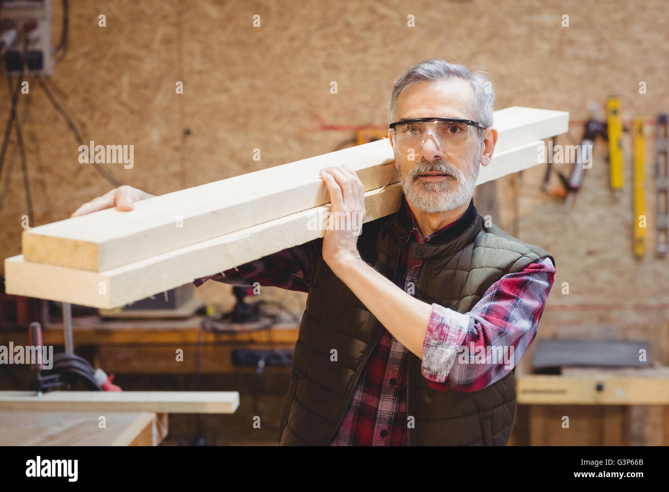 Portrait of a carpenter holding wood plank on his shoulder Stock Photo