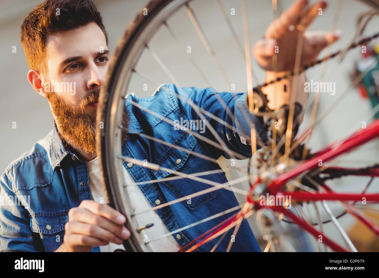 Portrait of a hipster repairing a bicycle wheel Stock Photo