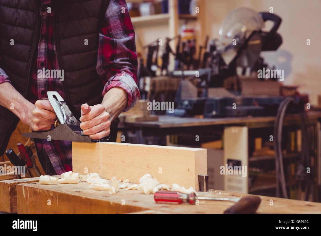 Portrait of carpenter perfecting wood plank form with a work tool Stock Photo
