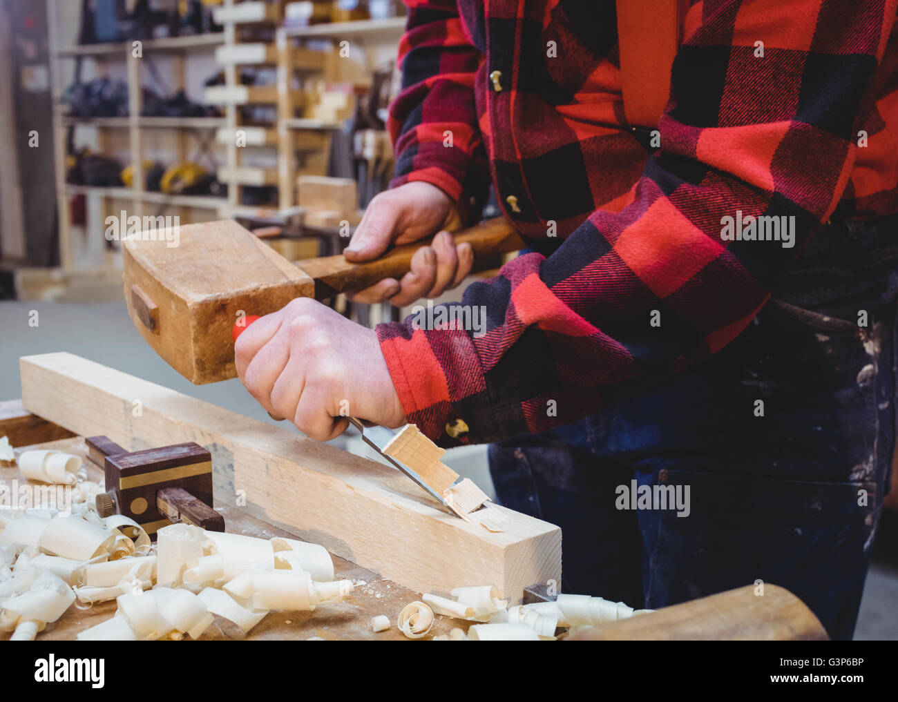 Carpenter working on a wooden plan with an hammer Stock Photo