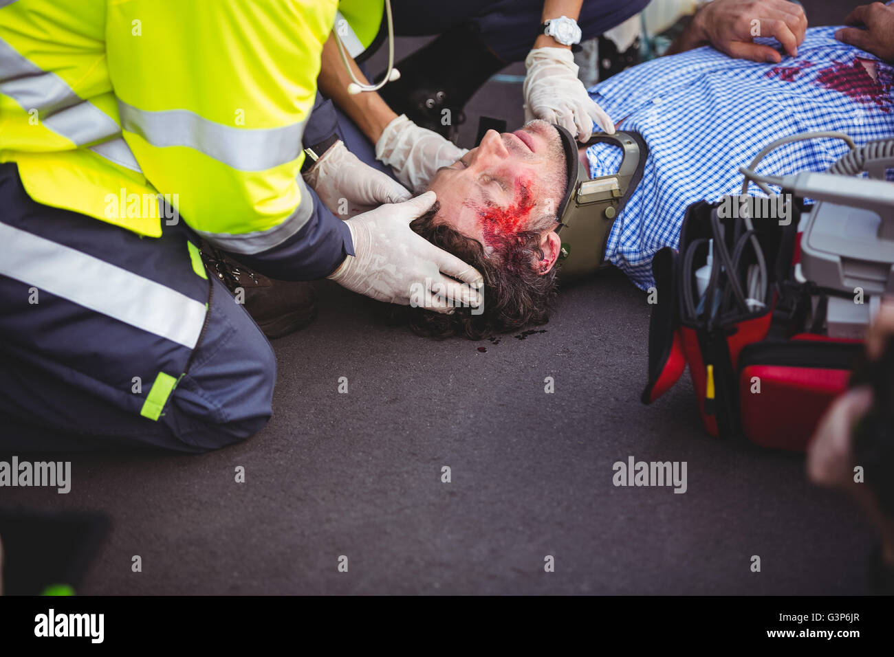 Injured man being taken care of by ambulance crew Stock Photo