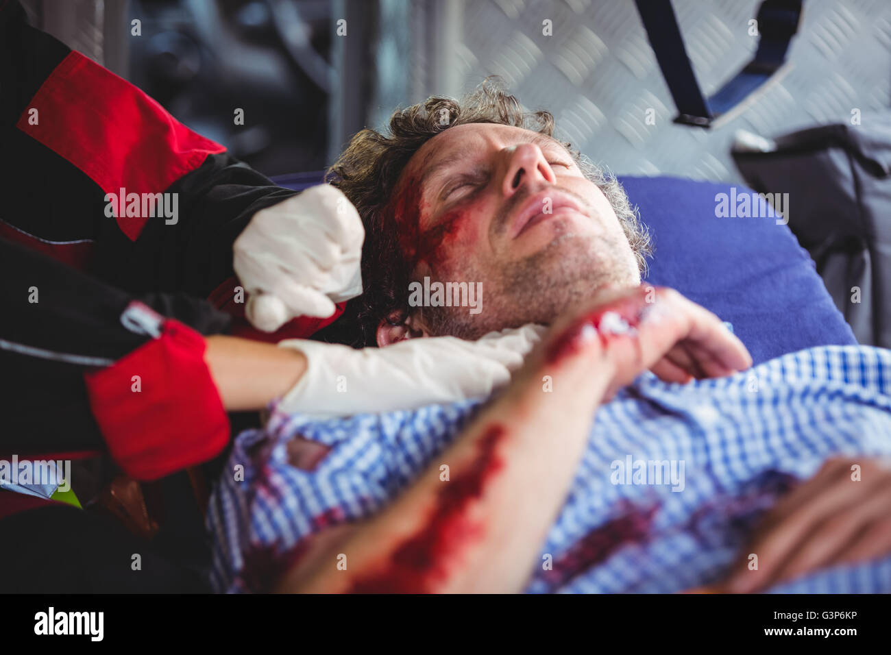 Injured man being taken care of ambulance crew Stock Photo