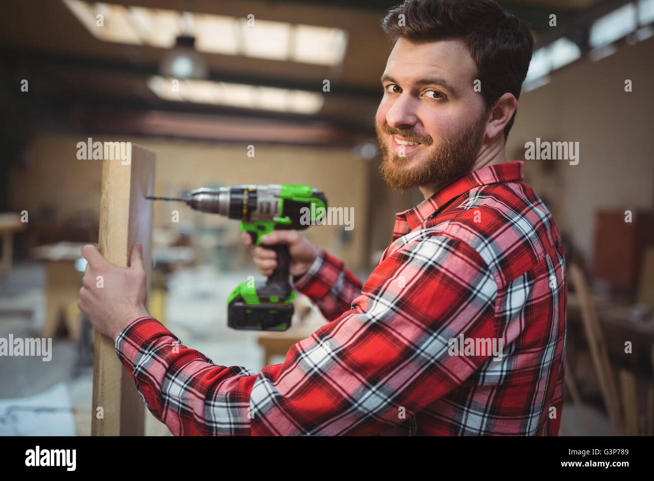Carpenter drilling a hole in a wooden plank Stock Photo