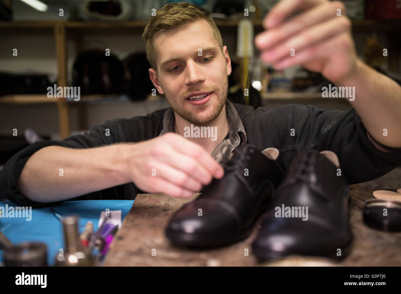 Cobbler putting lace on shoes Stock Photo