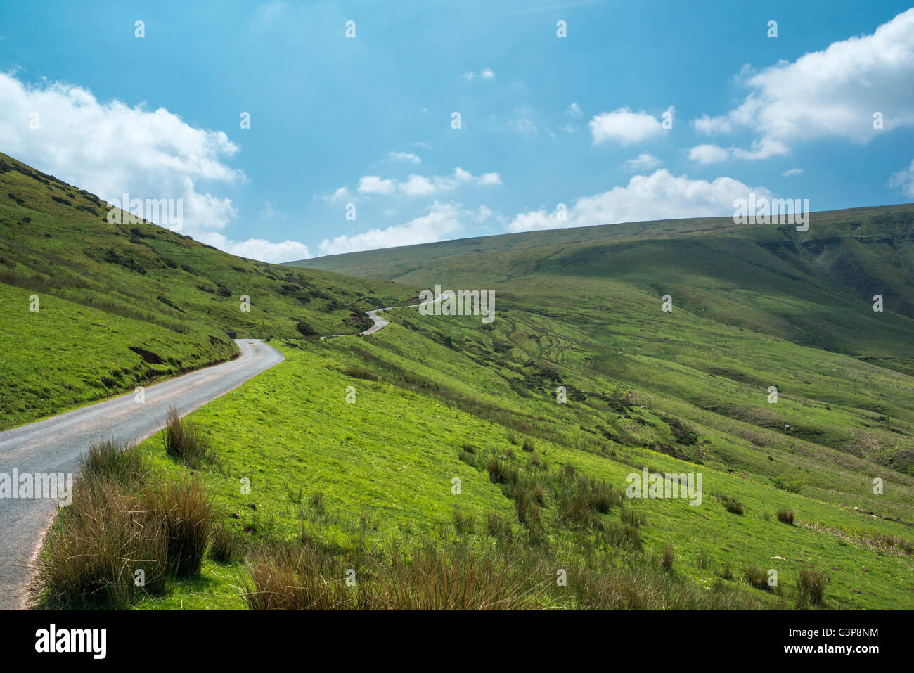 A country road in a valley, climbing towards a range of mountains. Stock Photo