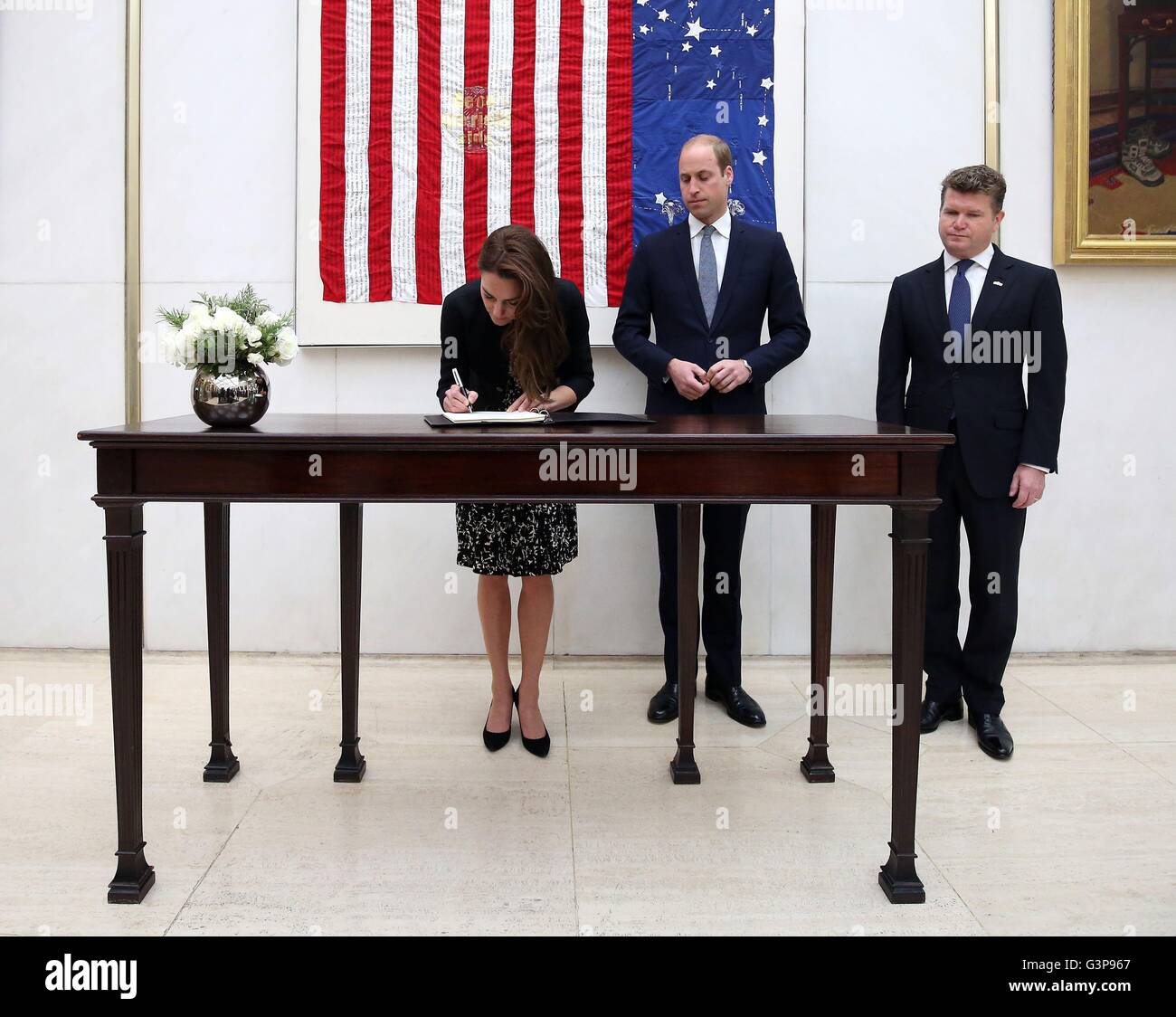 The Duchess of Cambridge signs a book of condolence for Orlando shooting victims at the US Embassy in London, while the Duke of Cambridge and Matthew Barzun, US Ambassador to London, look on. Stock Photo