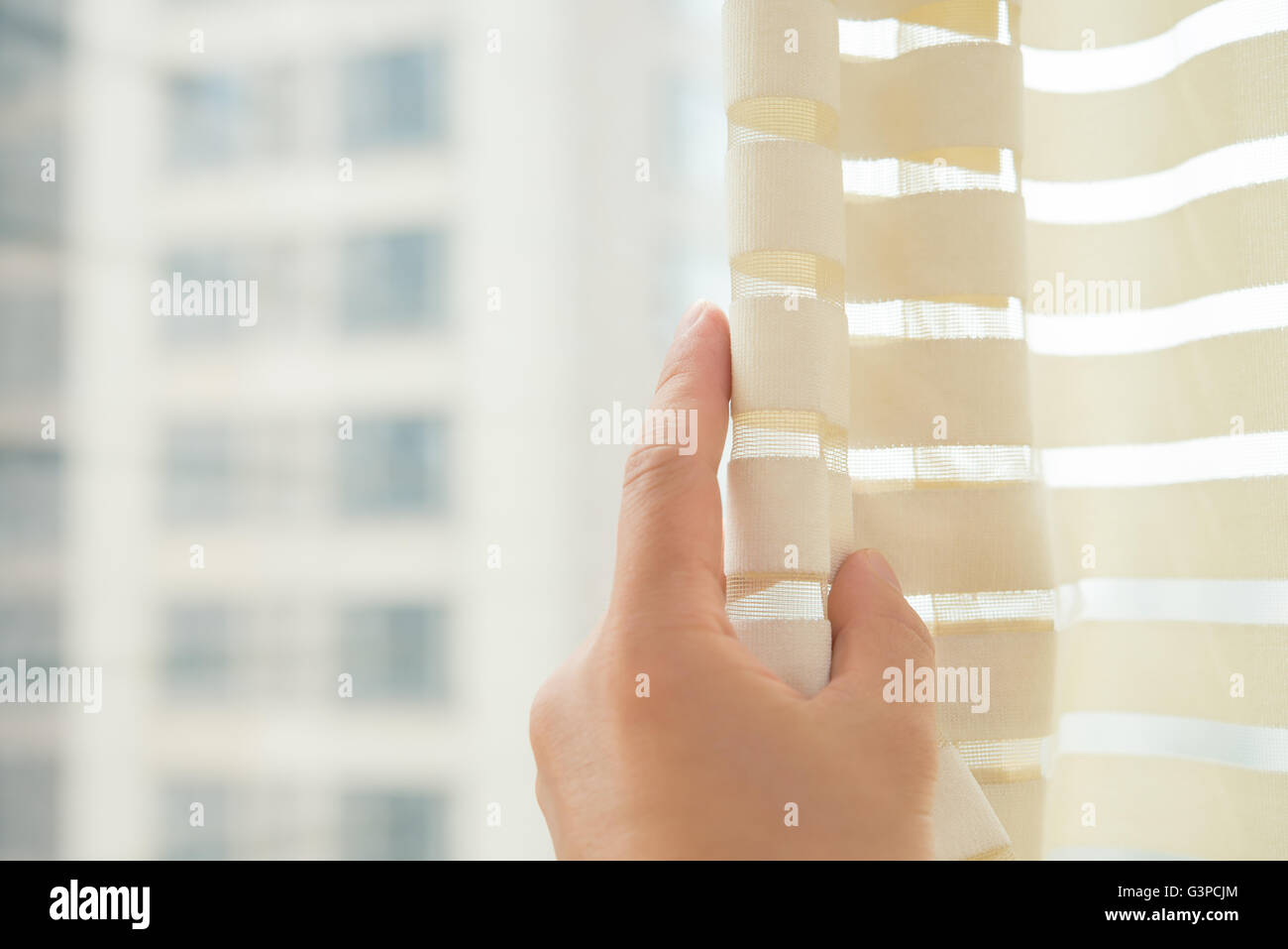 man gently opening the curtain in the bed room Stock Photo
