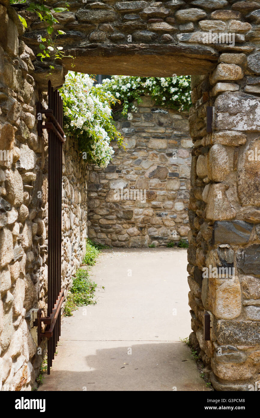 Stone wall with gated opening into courtyard Stock Photo
