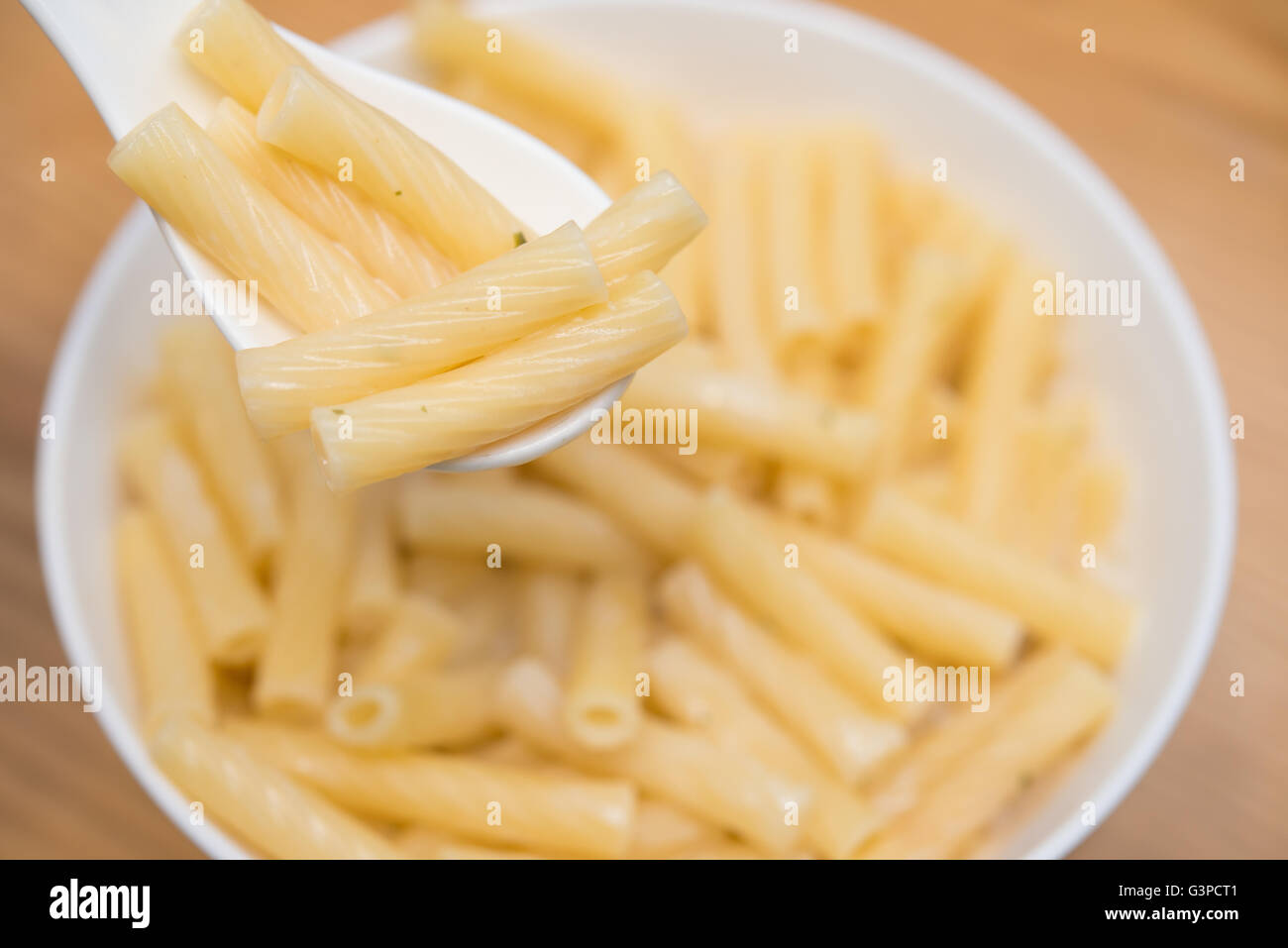 spoon taking out fresh italian pasta with cheese sauce from a bowl Stock Photo