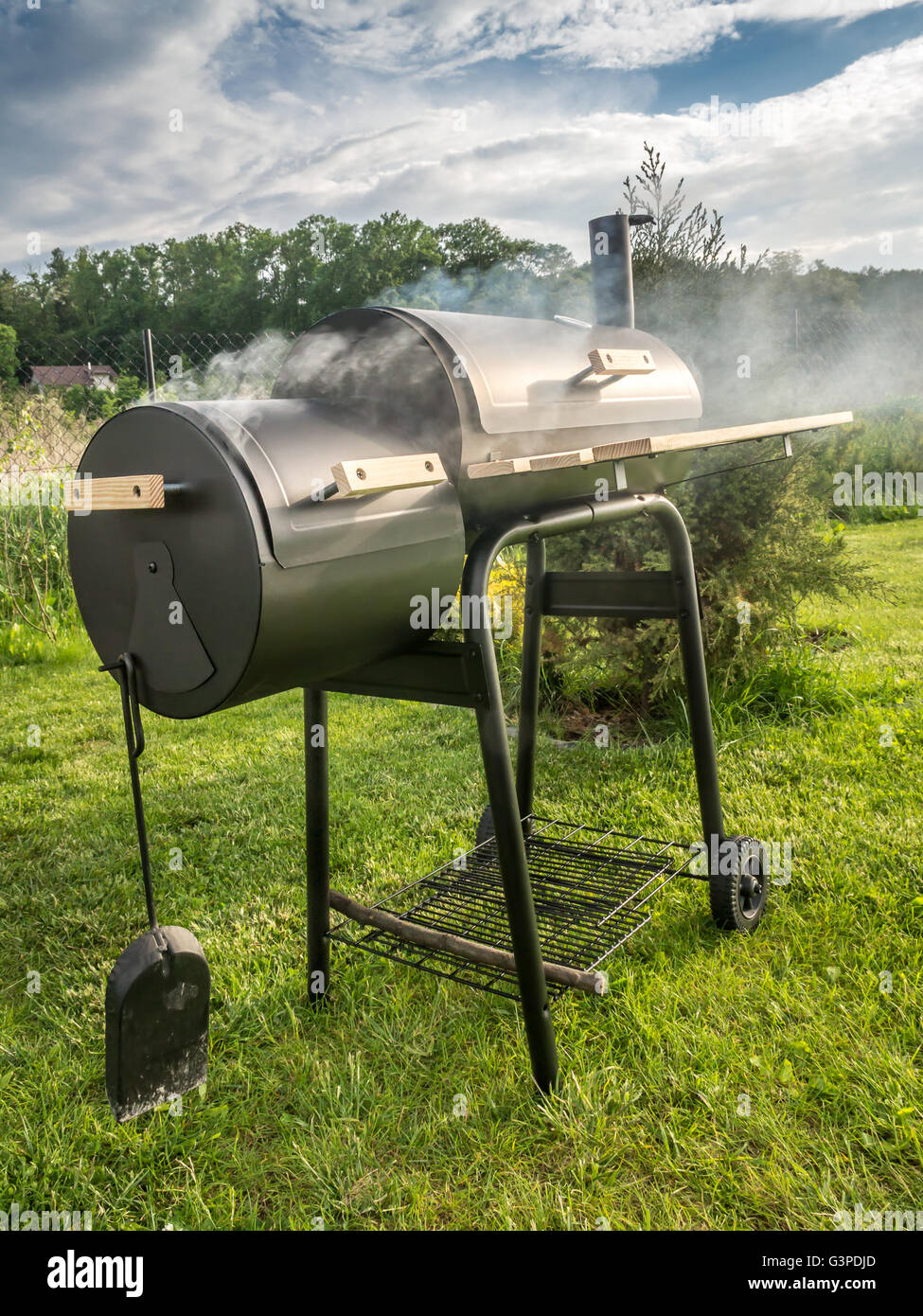 Barbeque meal being prepared using black grill with chimney in the backyard Stock Photo