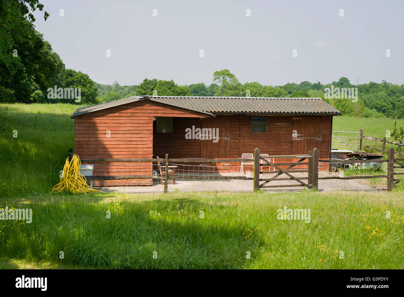 Stable block in a field in West Sussex. Post and rail fencing around