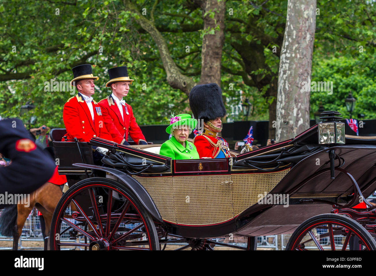 The Queen in a  green outfit waves from a carriage, accompanied by HRH The Duke Of Edinburgh on The Mall at The Trooping Of The Colour 2016,London, UK Stock Photo