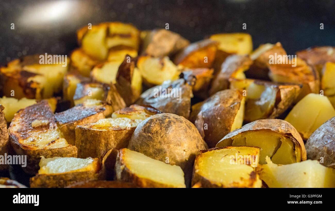 Roasted potato in a frying pan on wooden table Stock Photo