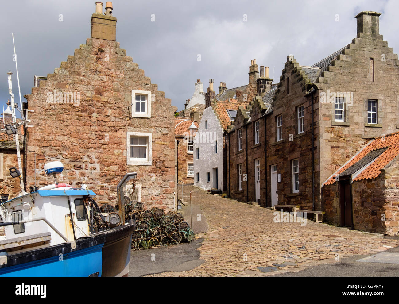 Fishing boat and old cottages on cobbled street by harbour in village on Firth of Forth coast. Crail East Neuk Fife Scotland UK Stock Photo
