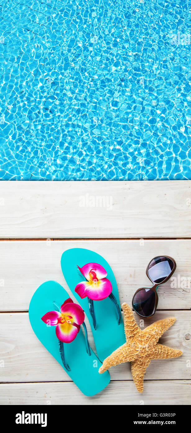 Beach Accessories On Wooden Desk Placed Over Swimming Pool