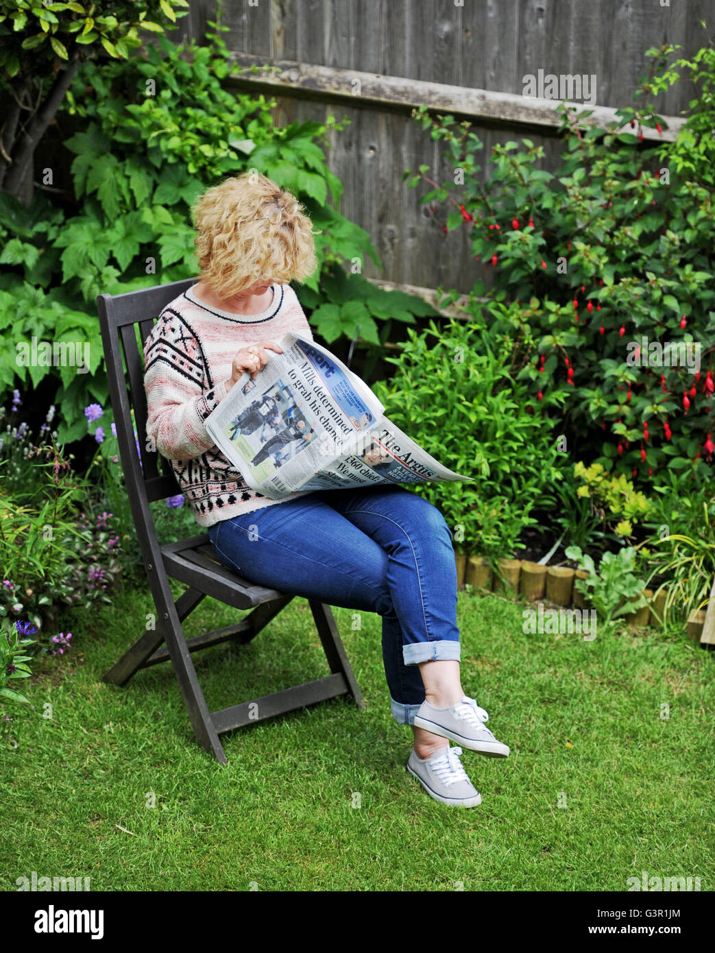 Woman reading a newspaper in the garden in summer UK Stock Photo Alamy