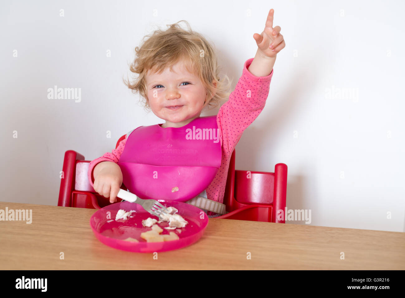 One Year Old Baby Sitting In High Chair And Eating Meal England