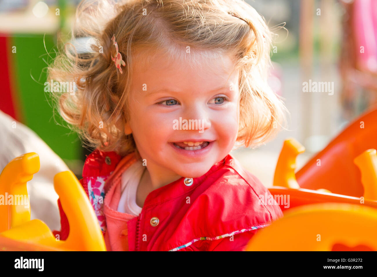 Blonde two year old girl enjoying a fairground ride, England, UK Stock Photo