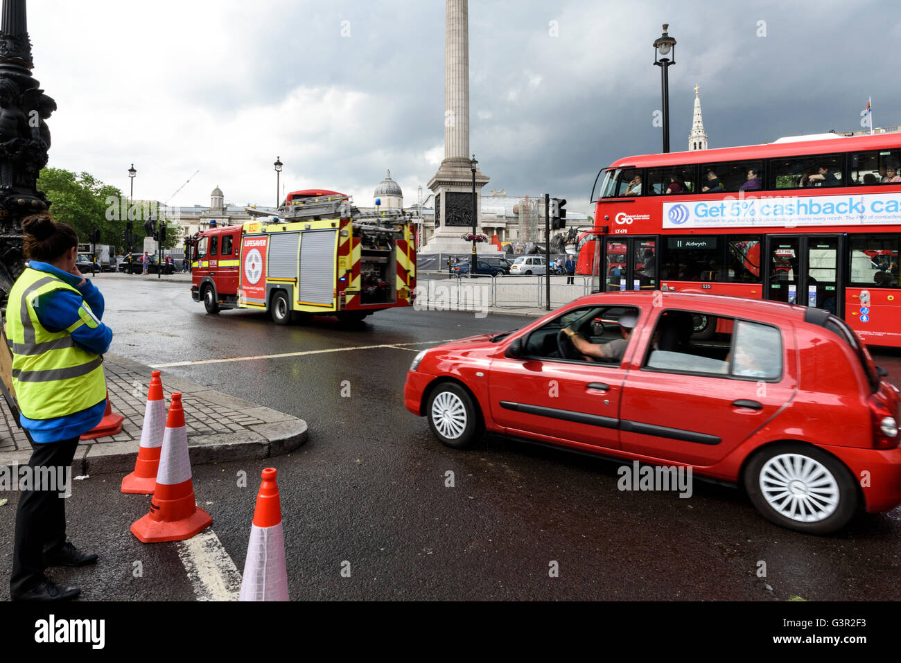 London fire engine, red double decker bus and red car at the Trafalgar Square roundabout, UK. Stock Photo