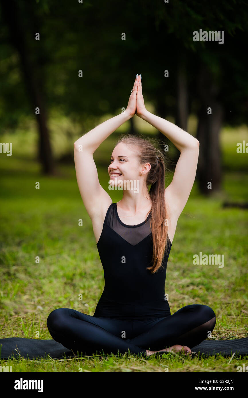 Woman in meditation pose Yoga on the green grass Stock Photo