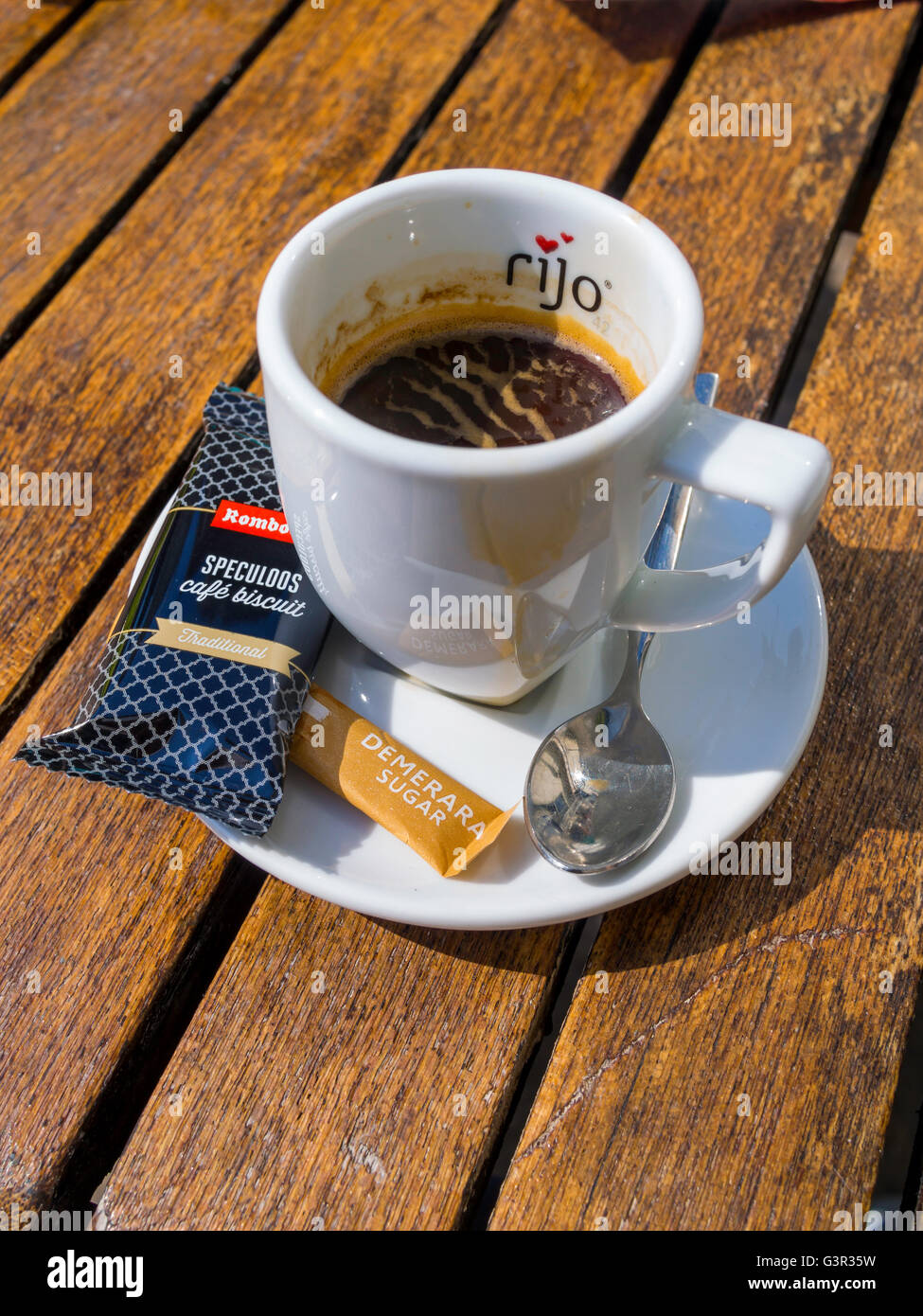 A cup of Rijo espresso coffee with a café biscuit and a pack of