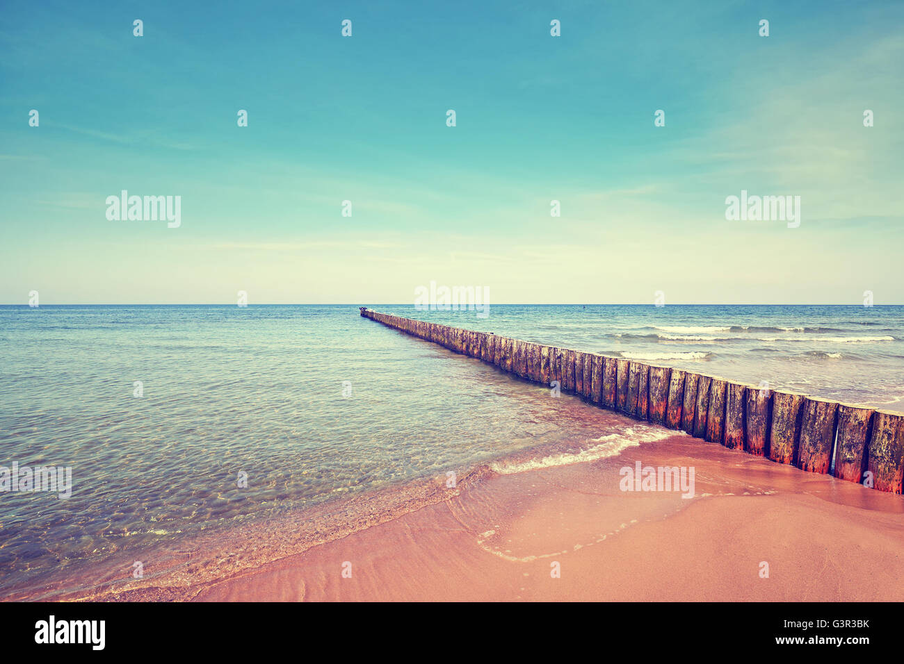 Retro toned beach with old wooden breakwater. Stock Photo