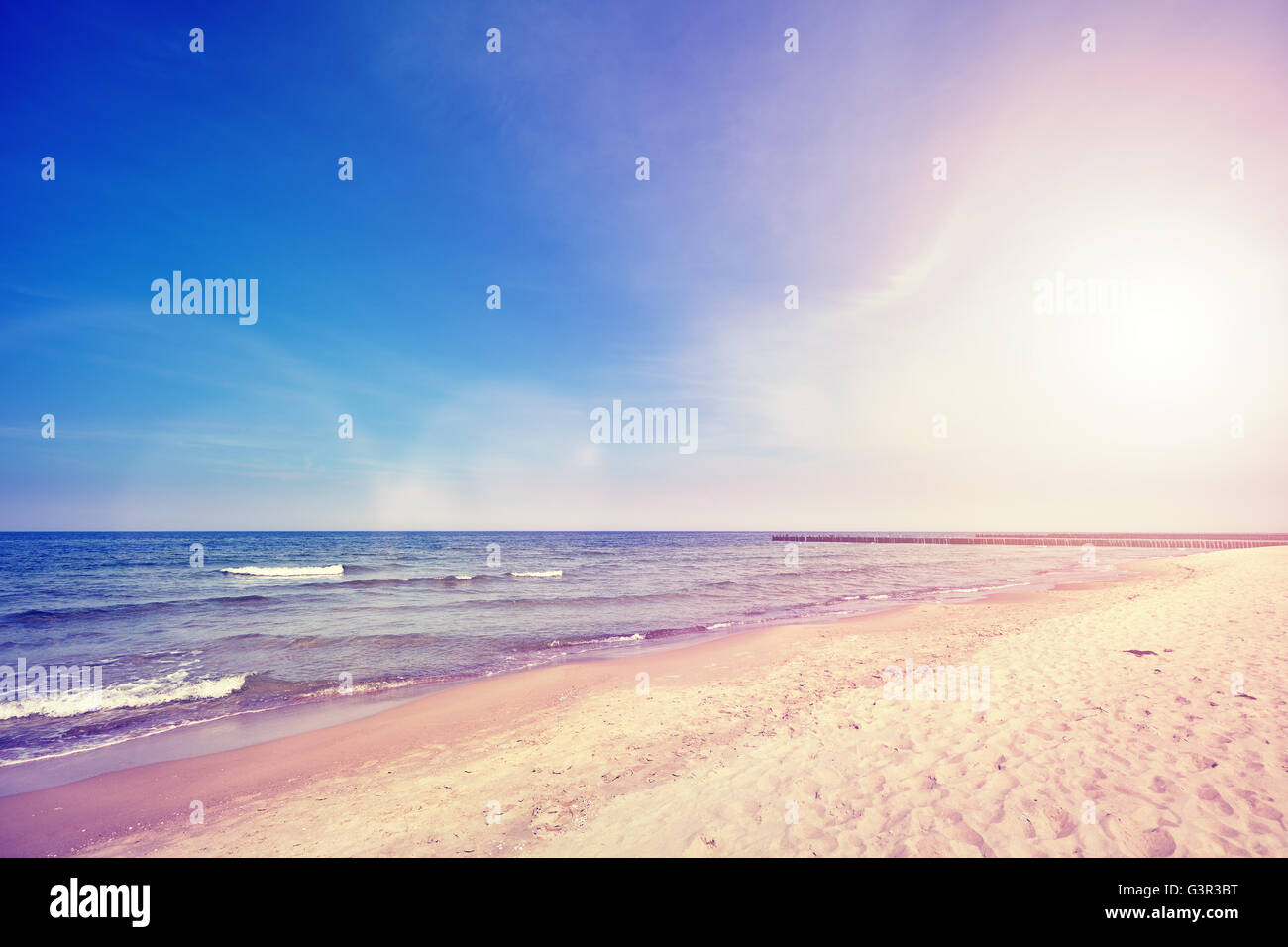 Vintage toned beach at sunset with lens flare effect, nature background. Stock Photo