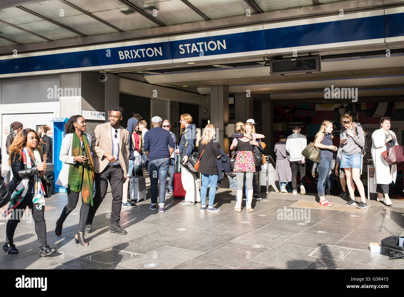People waiting and British-African couple walking in front of the entrance of Brixton Underground station in South London Stock Photo