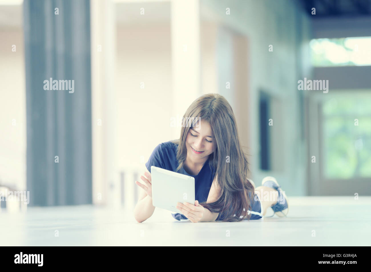 asia girl lying on floor and looking into tablet computer at home Stock Photo