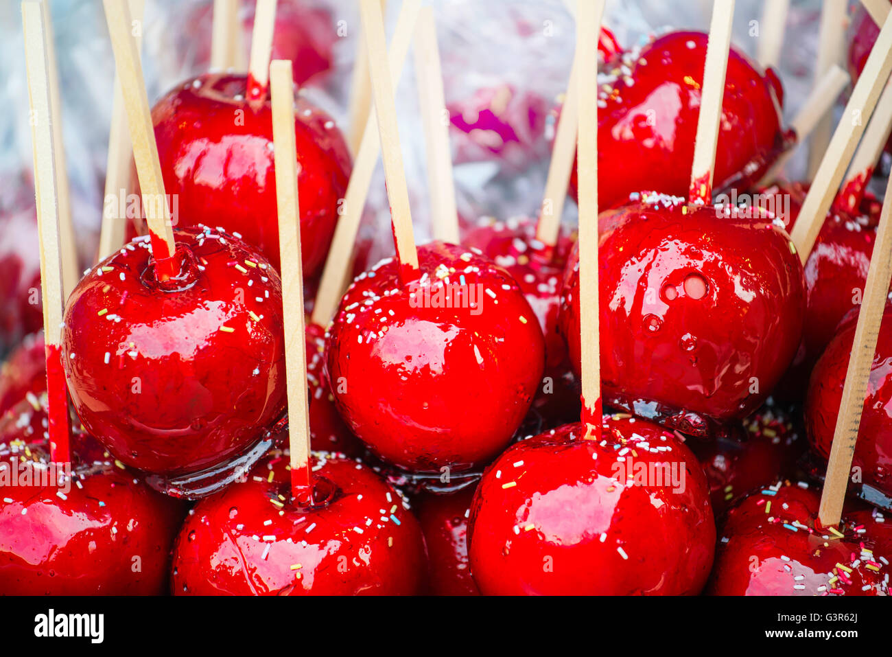 Sweet glazed red toffee candy apples on sticks for sale on farmer market or country fair. Stock Photo