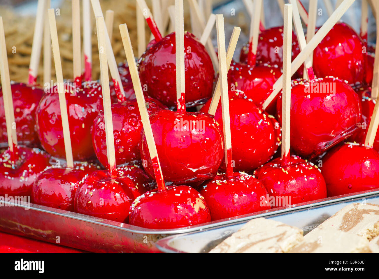 Sweet glazed red toffee candy apples on sticks for sale on farmer market or country fair. Stock Photo