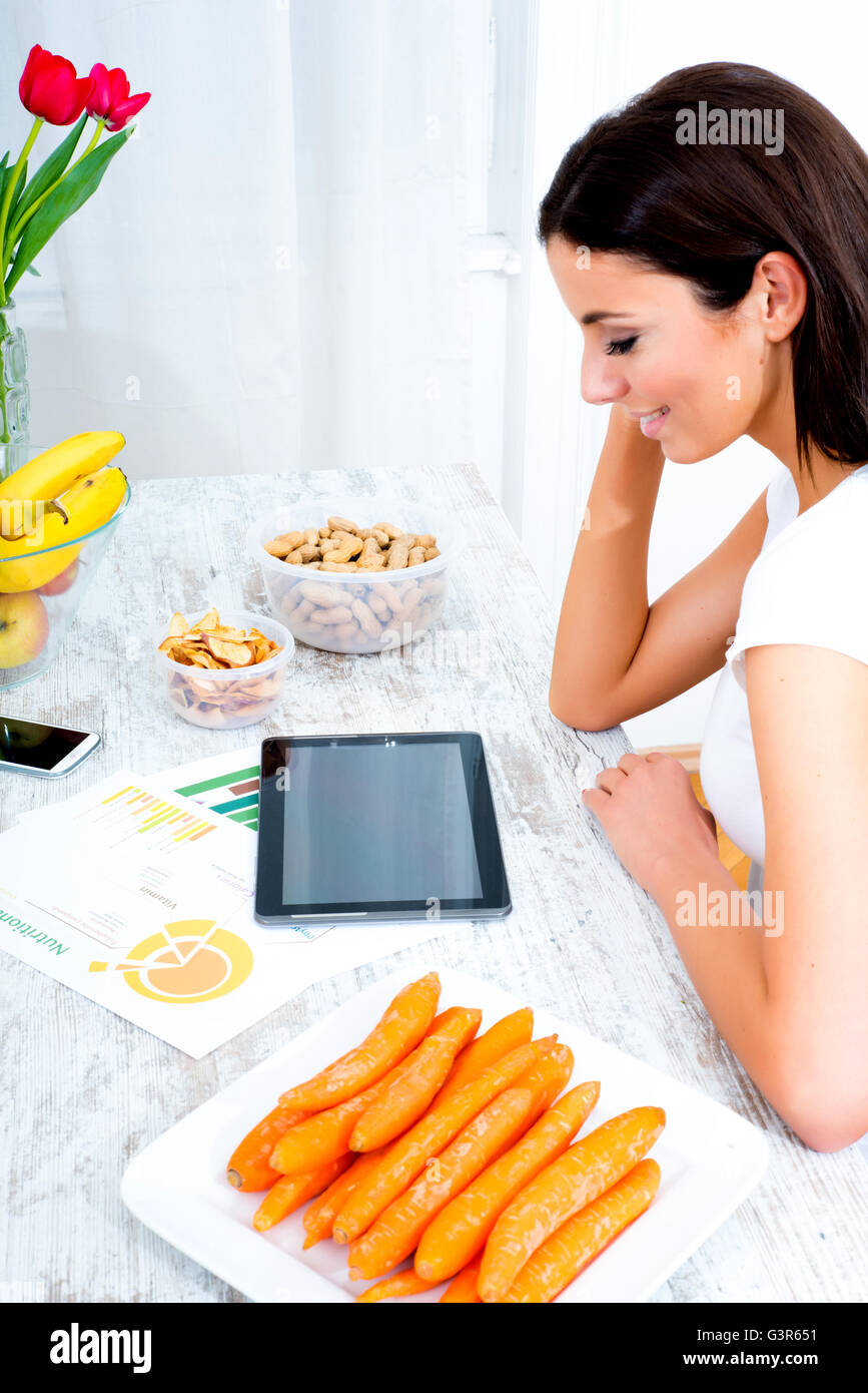 A young beautiful woman using a Tablet computer at home in the kitchen ...