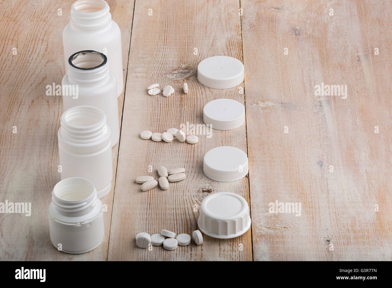 Various white plastic pill bottles and heap of drugs Stock Photo
