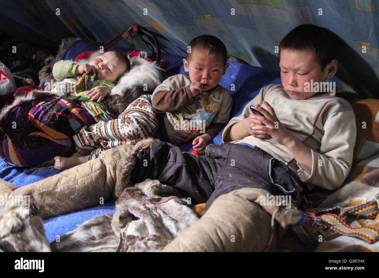No children played with a mobile phone inside the chum-traditional dwellings of Nenets reindeer breeders. Stock Photo