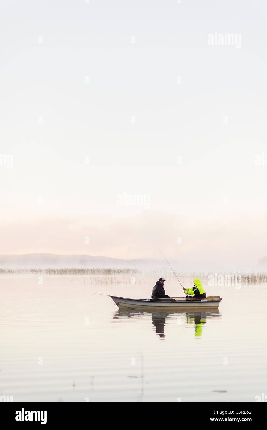 Sweden, Vastmanland, Bergslagen, Torrvarpen, Young men fishing in lake at sunset Stock Photo