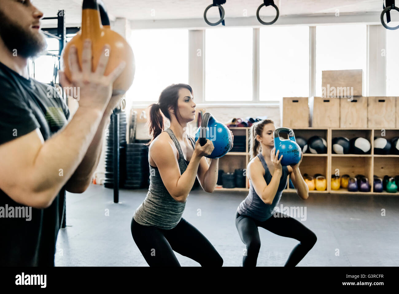Germany, Young women and man cross training with kettlebells in gym Stock Photo