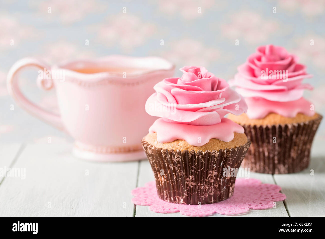 Cupcakes with sweet rose flowers and a cup of tee Stock Photo