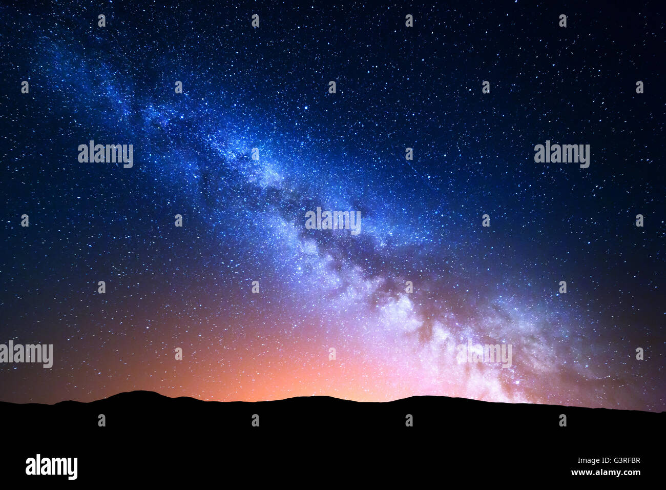 Night landscape with colorful Milky Way and yellow light at mountains. Starry sky with hills at summer. Beautiful Universe. Spac Stock Photo