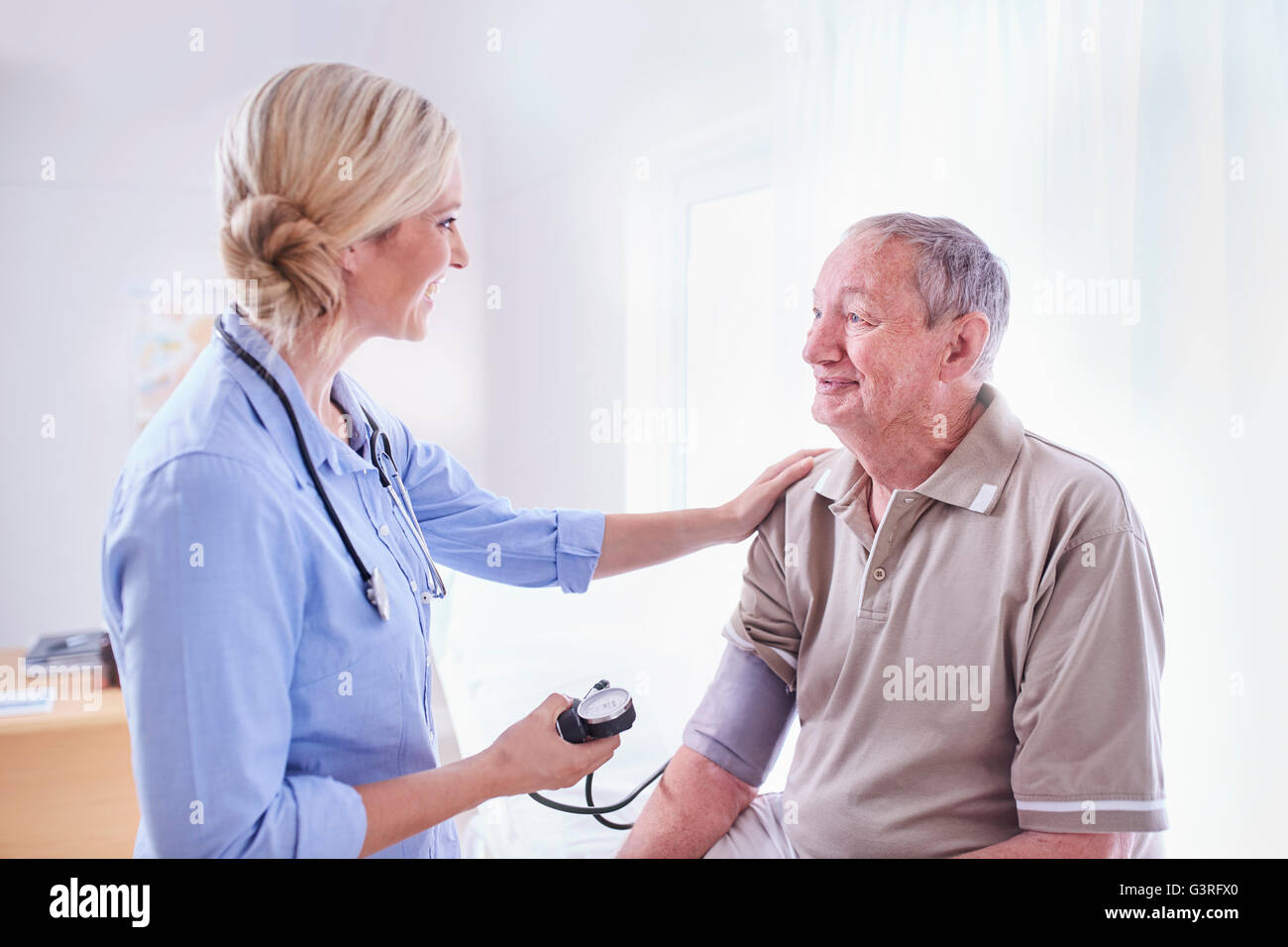 Doctor checking senior man’s blood pressure in checkup Stock Photo