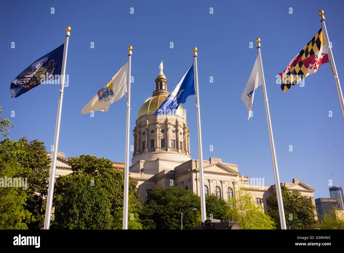 The golden capital dome stands out against a blue sky in Atlanta flags waving Stock Photo