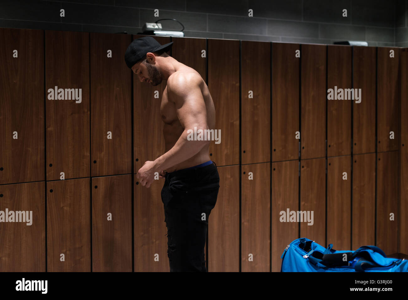 Young Fit Adult Man Changing Clothings In Locker Room Of Gym Facility Stock Photo