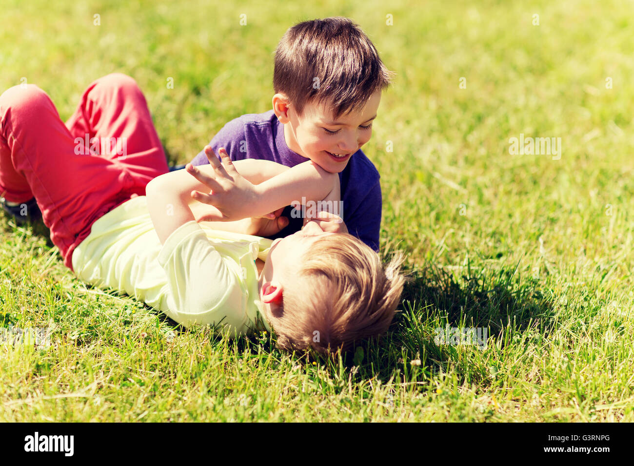 happy little boys fighting for fun on grass Stock Photo