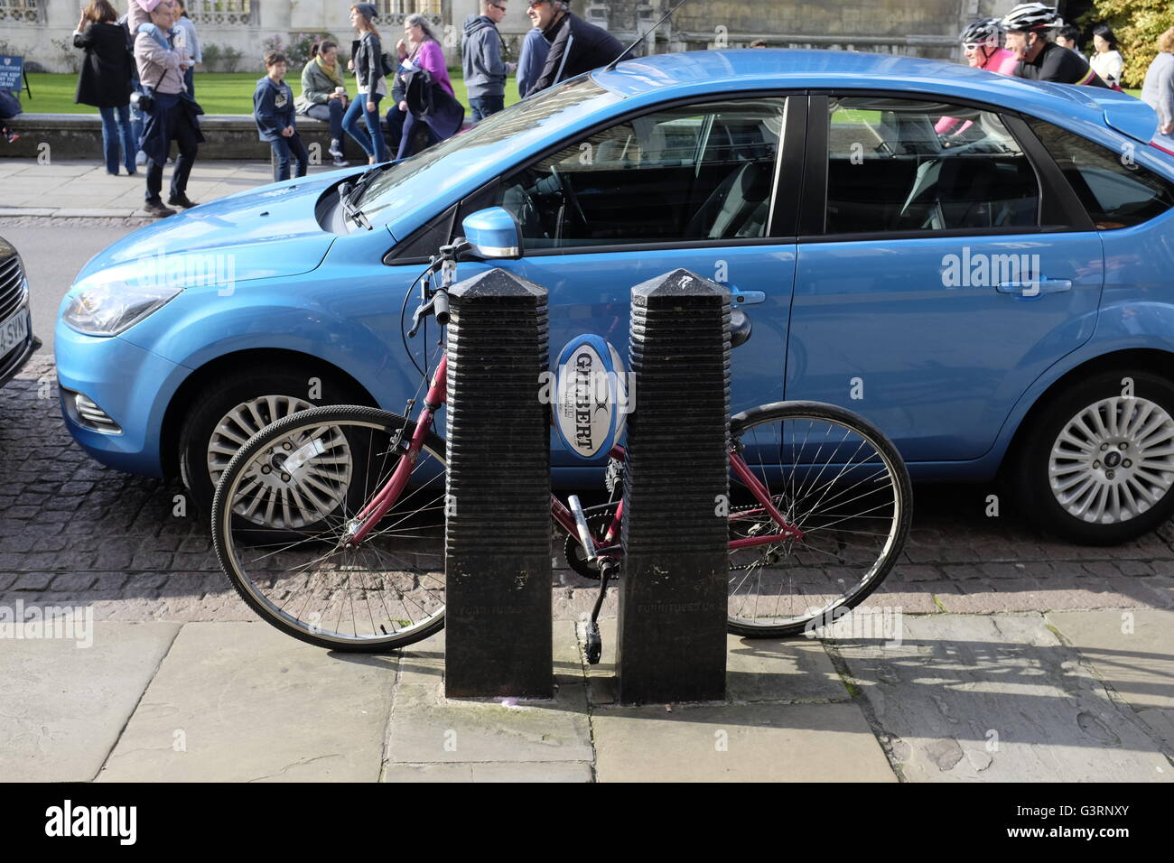 Bicycle parked against bollards with rugby ball wedged between bollards in Cambridge Stock Photo