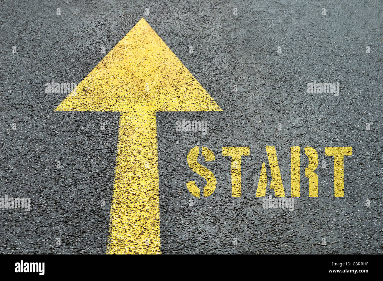 Yellow forward road sign with Start word on the asphalt road. Business concept. Stock Photo