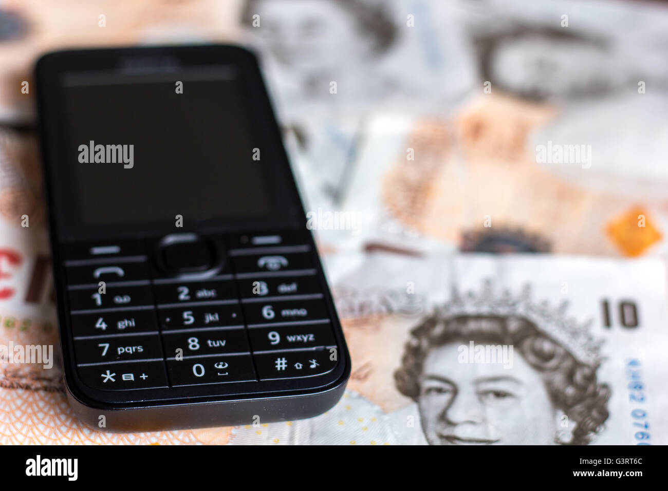 Mobile phone and ten pound note depicting cost of phones Stock Photo
