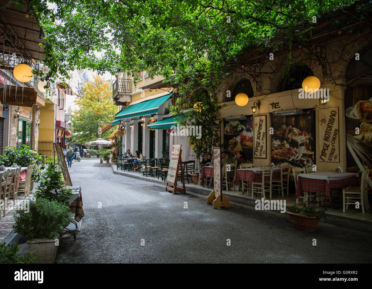Passing tavernas and restaurants, while walking through the streets of the historic neighborhood of Plaka in Athens, Greece. Stock Photo