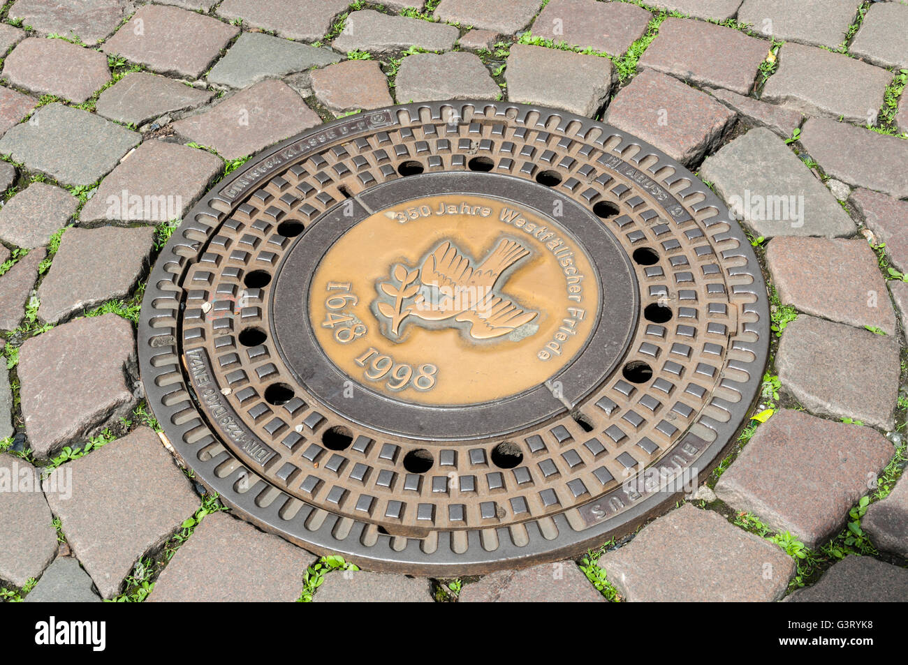 Decorative man-hole cover on cobbled street in Münster, NRW, Germany. Stock Photo