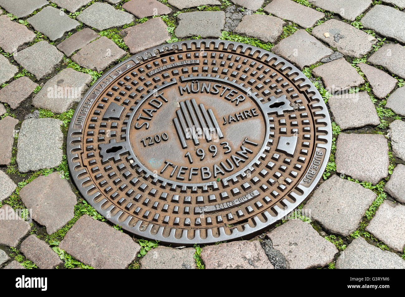 Decorative man-hole cover on cobbled street in Münster, NRW, Germany. Stock Photo