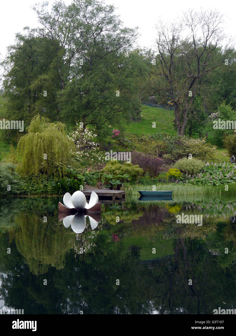 Rowing Boat and Pier with Floating Sculpture on a Lake at the Himalayan Garden & Sculpture Park, North Yorkshire, England UK. Stock Photo